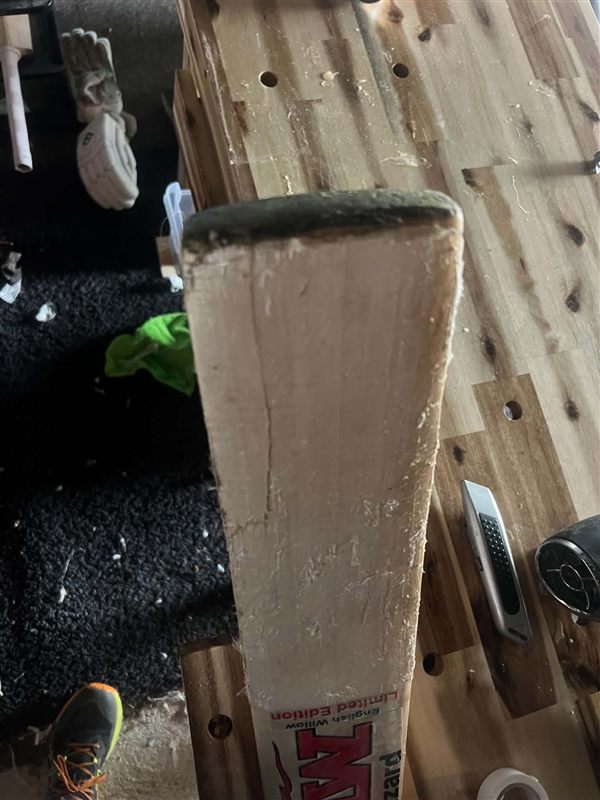 Before: bat face sanded back on the workbench, showing a long crack running up from the toe